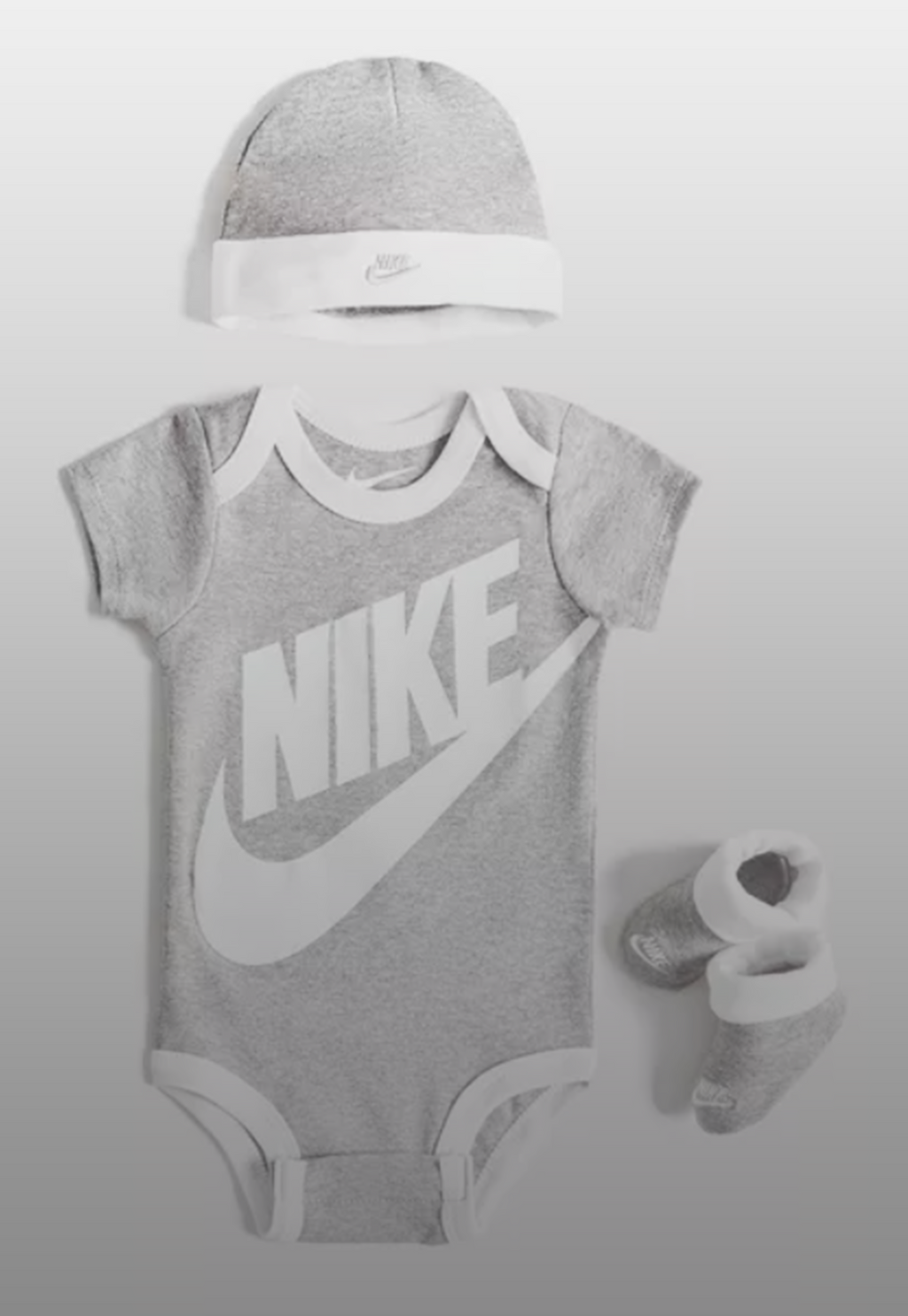 Nike set regalo neonato composto da 3 pezzi: body, cappellino e scarpine in cotone. Colorazione grigio e bianco
