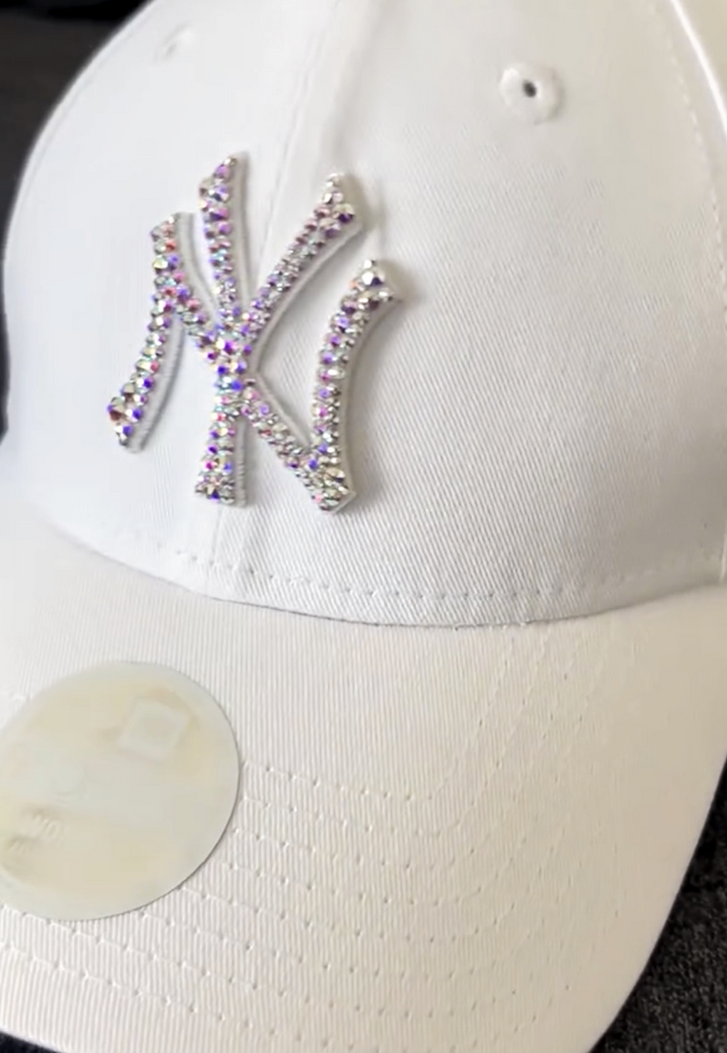 Acquista il cappello New Era NY Yankees personalizzato con brillantini color aurora cangianti: un accessorio esclusivo, glamour e streetwear, perfetto per look originali e idee regalo. Colore Cappello: Bianco