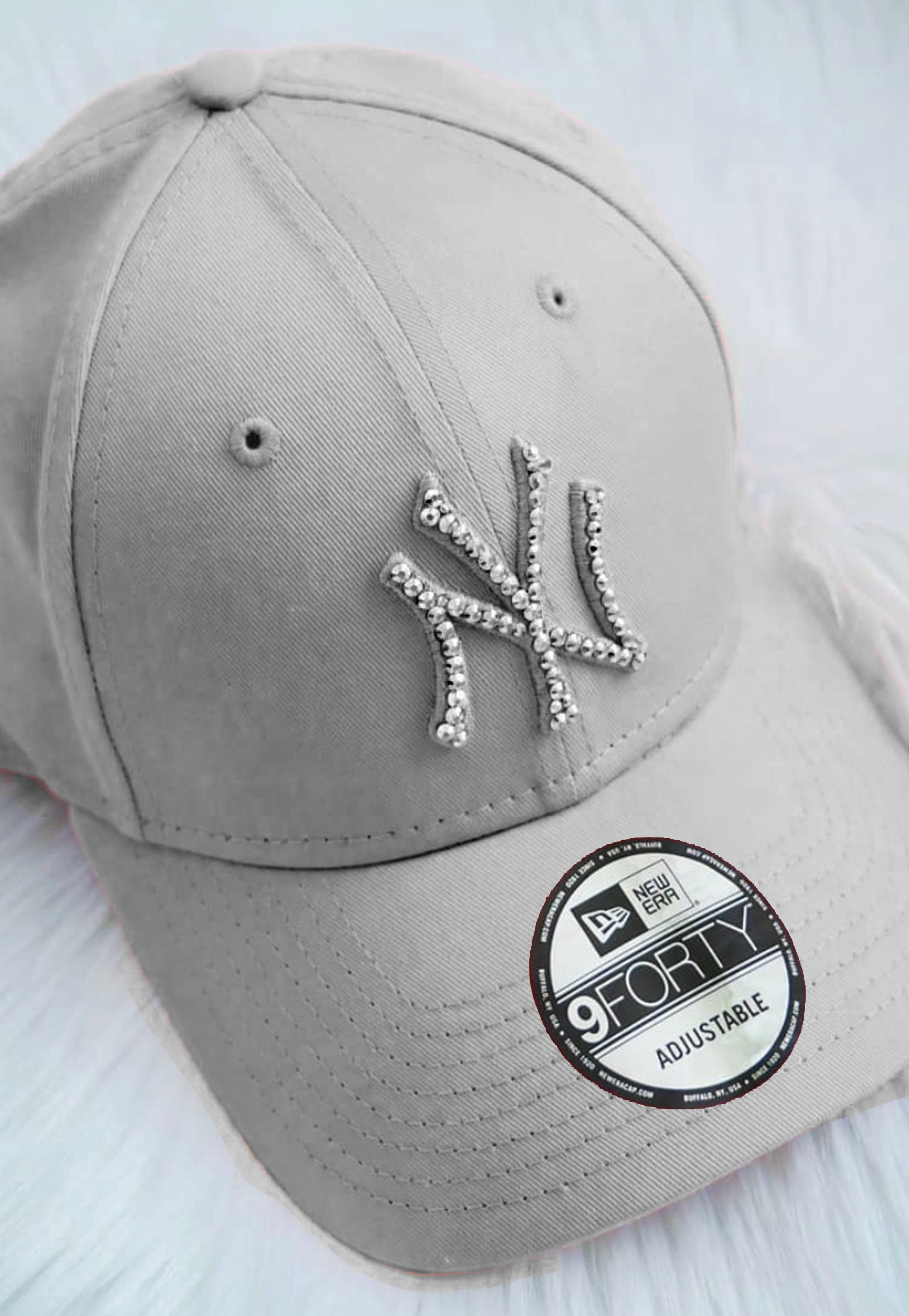 Acquista il cappello New Era NY Yankees personalizzato con brillantini color argento: un accessorio esclusivo, glamour e streetwear, perfetto per look originali e idee regalo. Cappello Colore Grigio